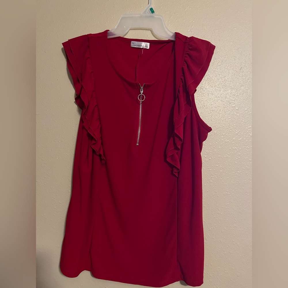 Red top, with Zippper closure. Ruffle sleeves.